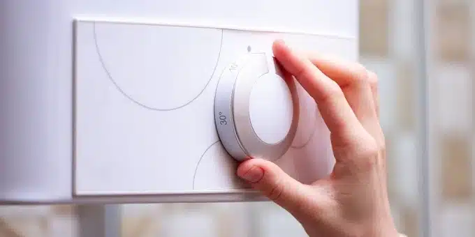 egy kéz lecsavarja a gázkazán termosztátját
